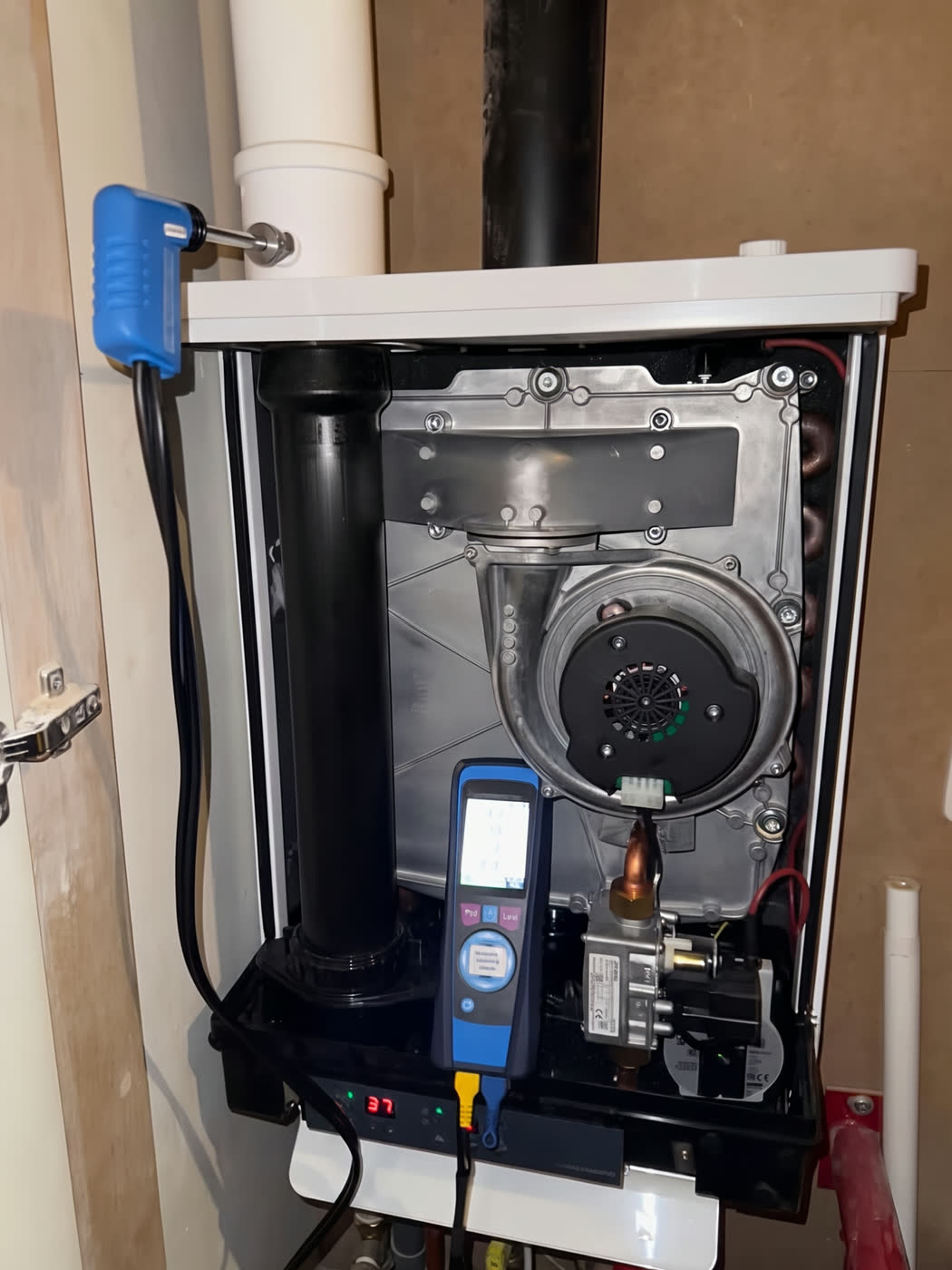 Geopende cv-ketel met een rookgasmeter aangesloten tijdens onderhoud